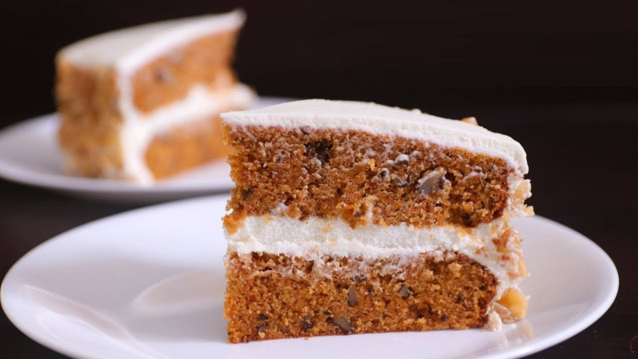 Slice of freshly baked sugar free carrot cake with creamy frosting on a white plate